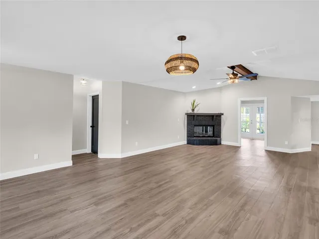 a view of an empty room with a window and wooden floor