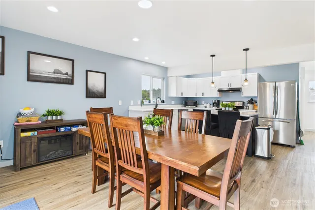 a dining room with stainless steel appliances kitchen island granite countertop a dining table chairs and a refrigerator