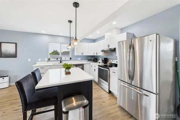 a kitchen with stainless steel appliances a dining table chairs and refrigerator