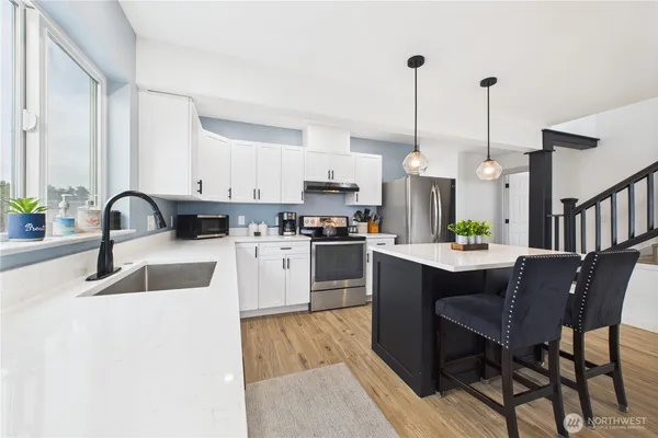 a kitchen with granite countertop a sink stainless steel appliances and white cabinets