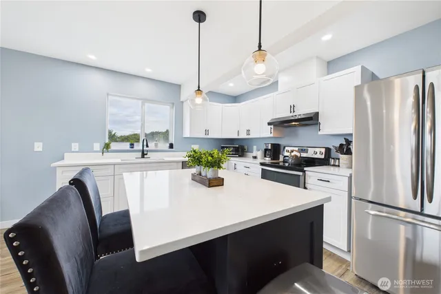 a kitchen with stainless steel appliances a table chairs refrigerator and microwave