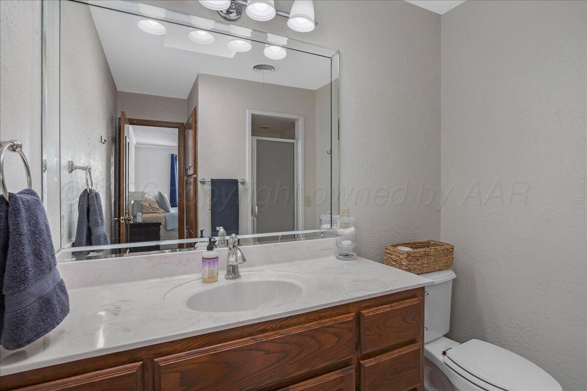 4202 Charles Street Amarillo, TX 79106 - Photo 18 of 27 a bathroom with a granite countertop sink a toilet and mirror