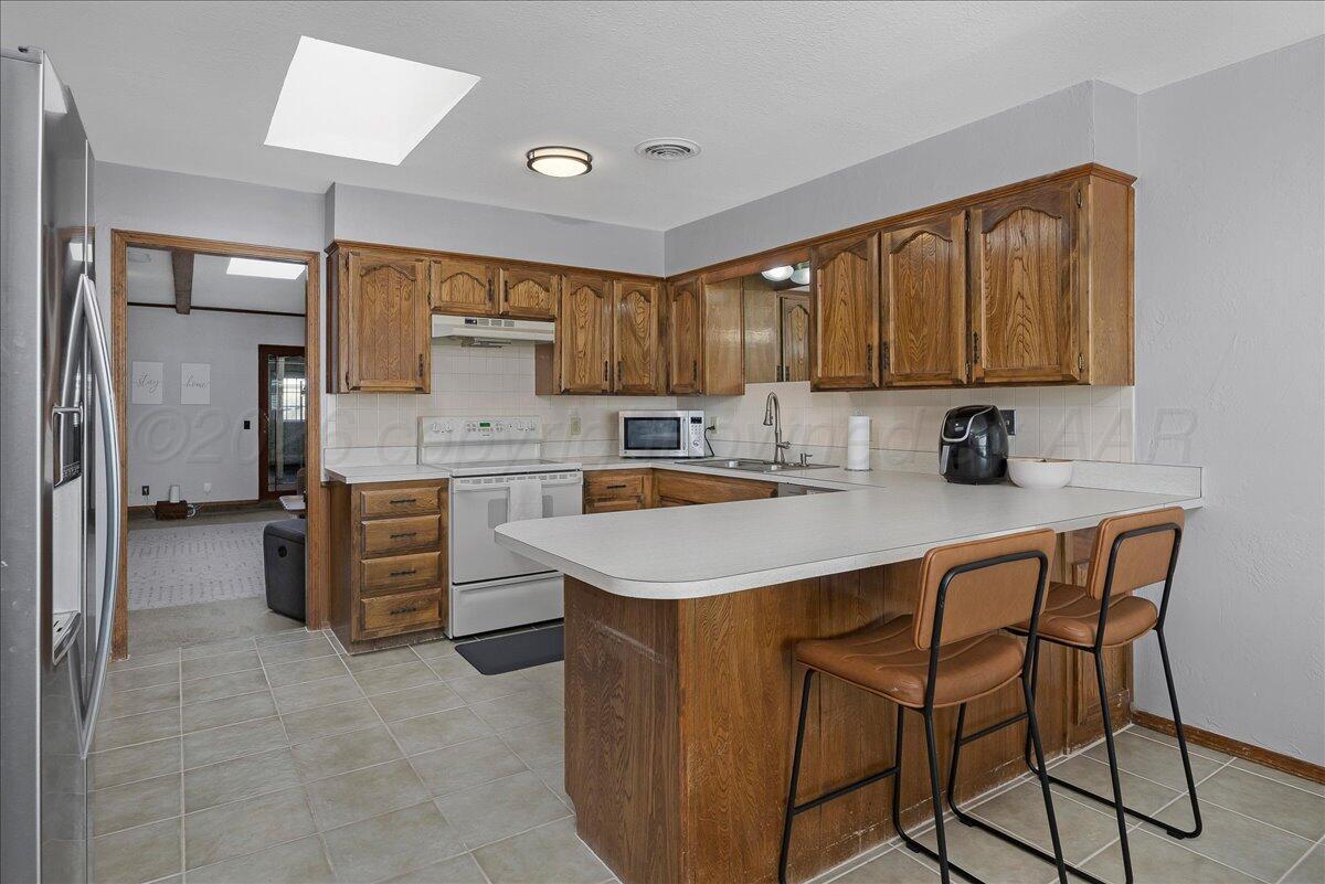 4202 Charles Street Amarillo, TX 79106 - Photo 8 of 27 a kitchen with stainless steel appliances granite countertop a sink stove and refrigerator