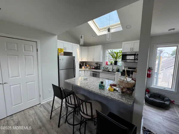 a kitchen with granite countertop kitchen island stainless steel appliances a refrigerator stove top oven and sink