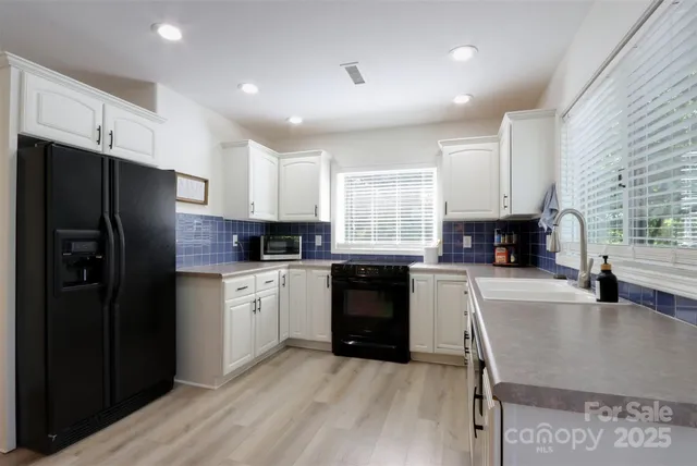 a kitchen with granite countertop a refrigerator stove top oven and sink