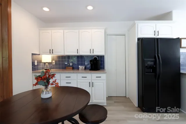 a kitchen with stainless steel appliances granite countertop a dining table chairs refrigerator and cabinets