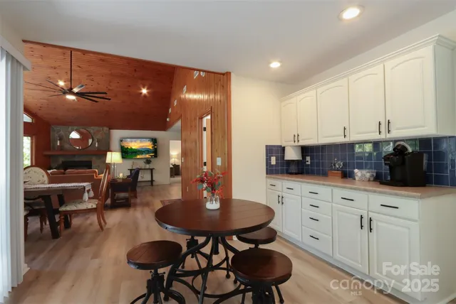 a kitchen with stainless steel appliances kitchen island granite countertop a table chairs sink and white cabinets