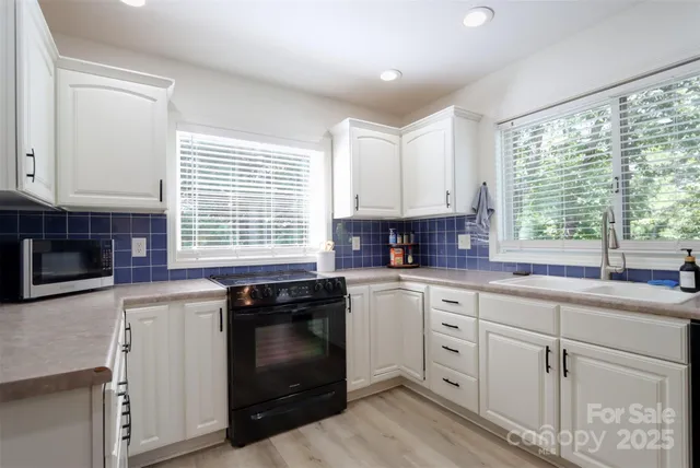 a kitchen with stainless steel appliances granite countertop white cabinets and a sink