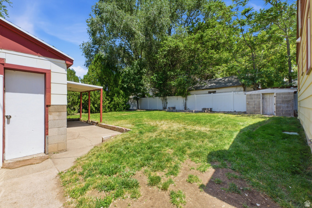 94 West 2000th Street North Clearfield, UT 84015 - Photo 21 of 26 Fenced backyard with lawn space, mature trees, detached garage, and patio area.