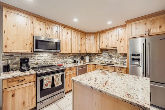 a kitchen with stainless steel appliances granite countertop a refrigerator stove microwave and sink