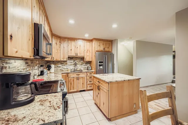 a kitchen with granite countertop a sink stove refrigerator and cabinets