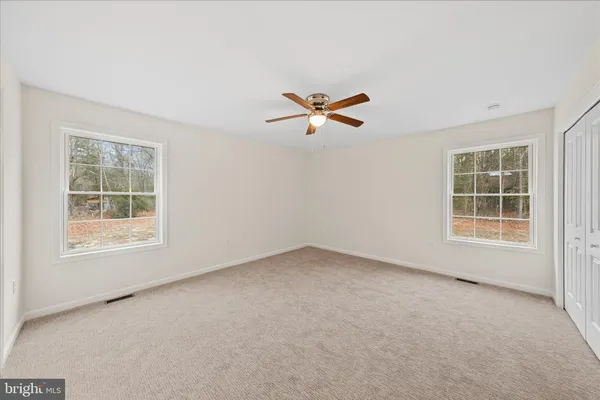 an empty room with a window and a ceiling fan