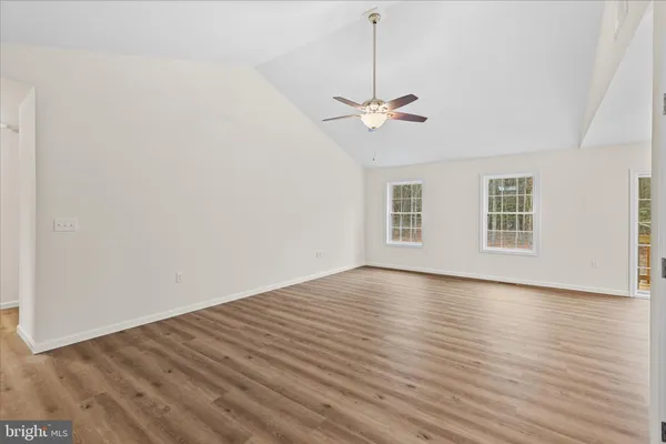 a view of empty room with wooden floor and ceiling fan