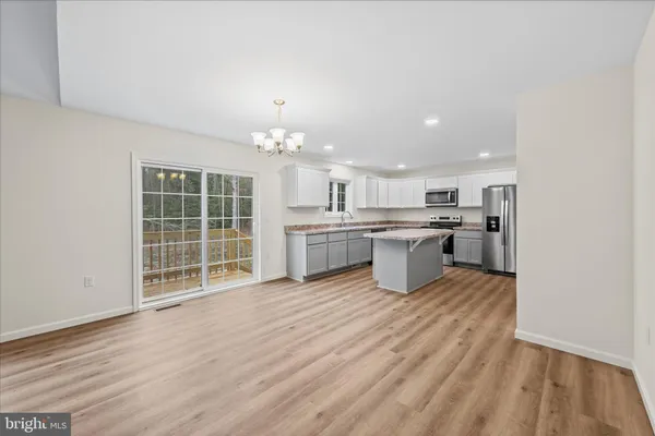an empty room with wooden floor and kitchen view