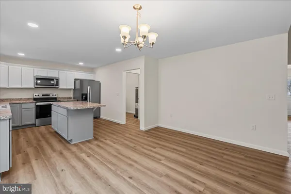 a kitchen with stainless steel appliances granite countertop a wooden floors and white walls