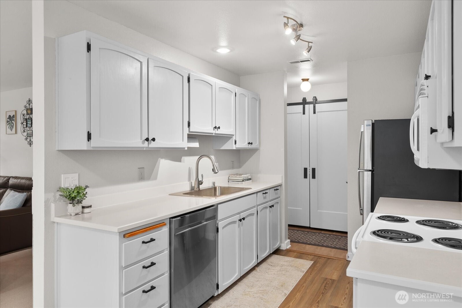 4120 212th Street Southwest, Unit B206 Mountlake Terrace, WA 98043 - Photo 5 of 20 a kitchen with a sink dishwasher a stove a refrigerator and white cabinets