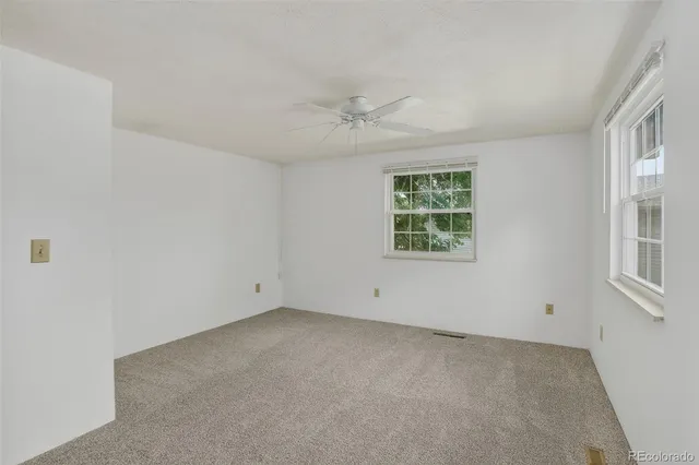 an empty room with windows and ceiling fan view