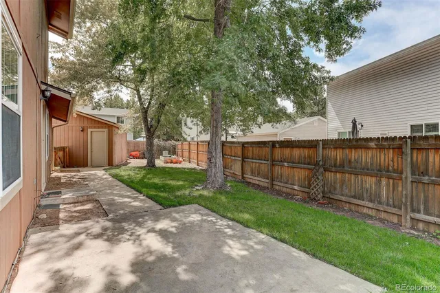 a view of a backyard with wooden fence and a bench