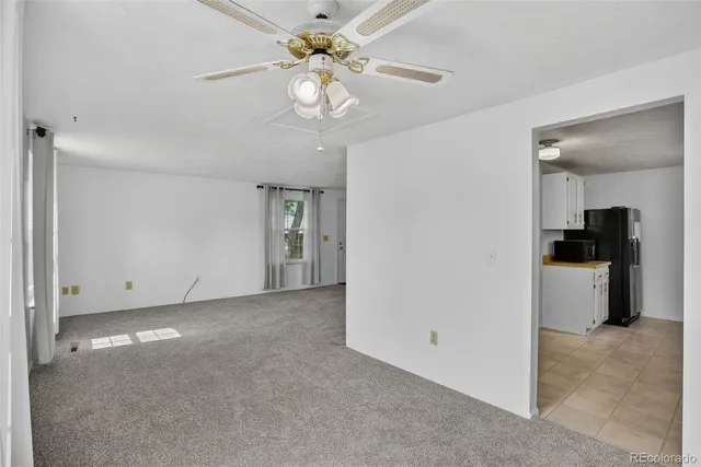 a view of a room with a ceiling fan and a refrigerator