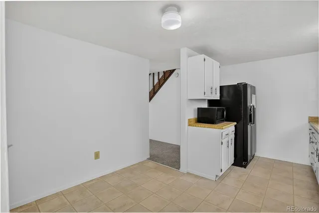a kitchen with a refrigerator and white cabinets