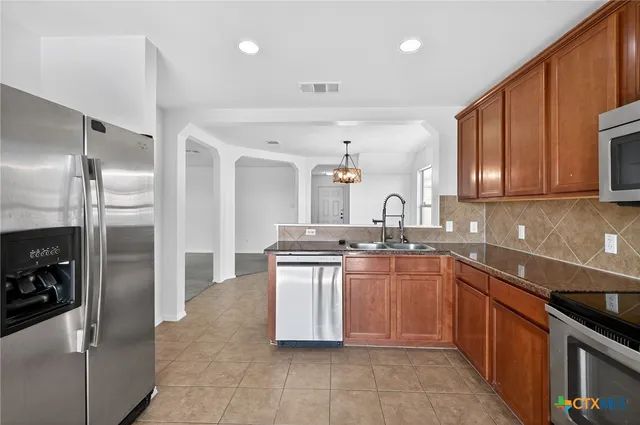 a kitchen with stainless steel appliances granite countertop a sink stove and refrigerator