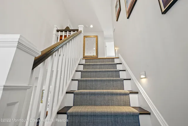 a view of staircase with lots of frames on wall and a potted plant