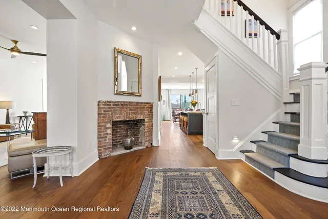 a view of a livingroom with furniture a fireplace chandeliers fan and windows