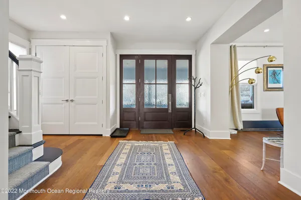 a view of a hallway with wooden floor and a bathroom