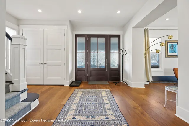 a view of a hallway with wooden floor and a bathroom