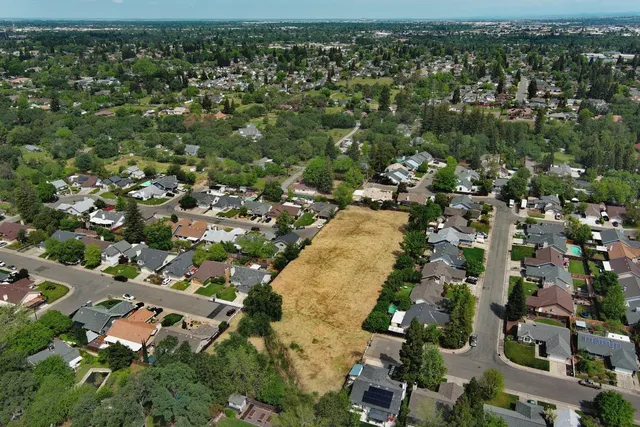 an aerial view of residential houses with outdoor space and trees