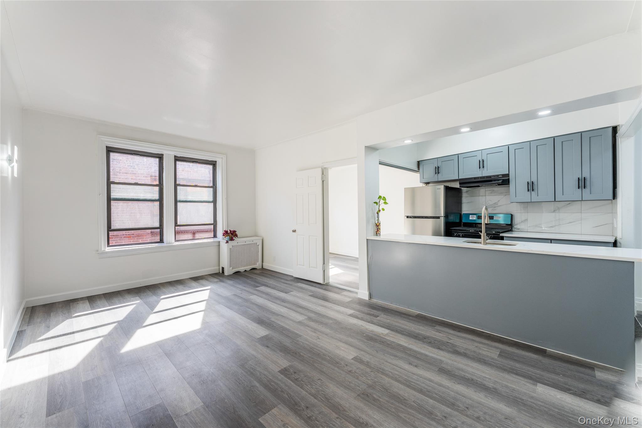 136-05 Sanford Avenue, Unit 6S Queens, NY 11355 - Photo 2 of 15 a kitchen with granite countertop white cabinets and wooden floor