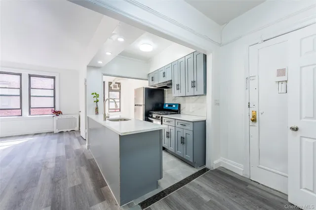 a kitchen with stainless steel appliances granite countertop a refrigerator a sink dishwasher a stove and white countertops with wooden floor