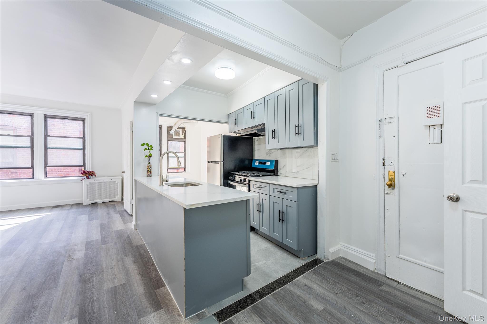 136-05 Sanford Avenue, Unit 6S Queens, NY 11355 - Photo 4 of 15 a kitchen with stainless steel appliances granite countertop a refrigerator a sink dishwasher a stove and white countertops with wooden floor