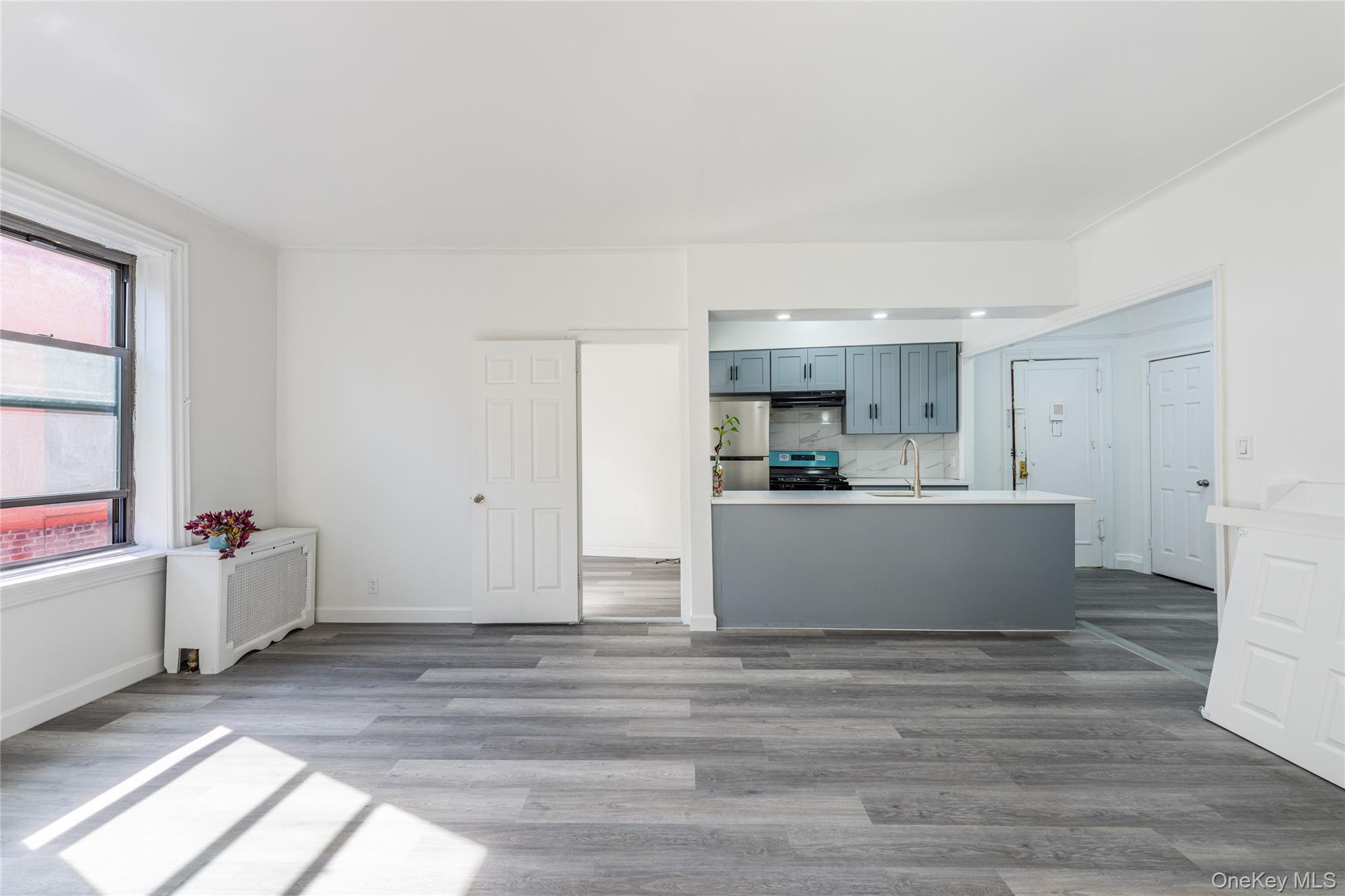 136-05 Sanford Avenue, Unit 6S Queens, NY 11355 - Photo 6 of 15 a view with kitchen island refrigerator sink microwave and cabinets