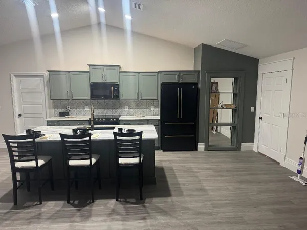a kitchen with stainless steel appliances kitchen island granite countertop a refrigerator and a stove top oven