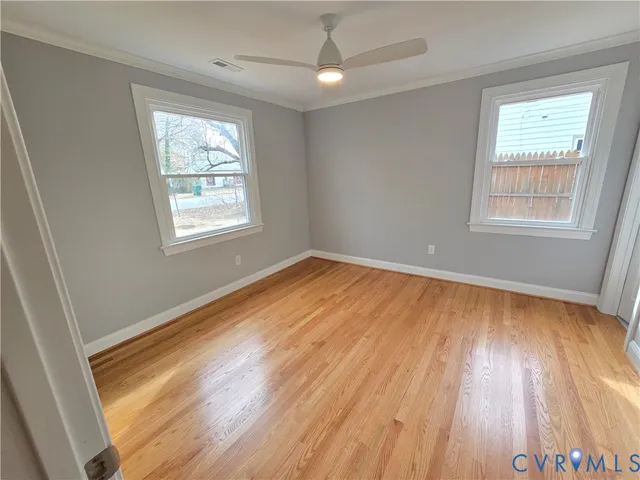 a view of empty room with wooden floor and fan