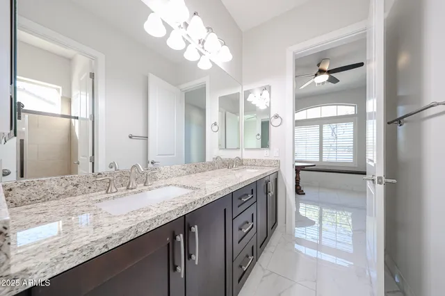 a bathroom with a granite countertop sink a light fixture and a mirror