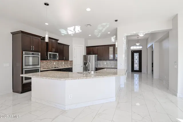 a large kitchen with stainless steel appliances kitchen island a large counter top and a refrigerator