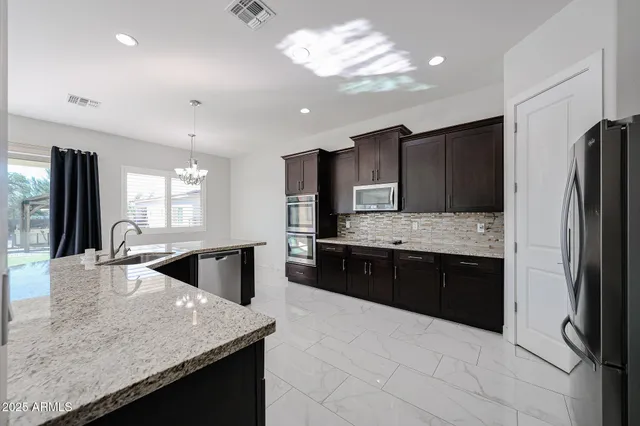 a large kitchen with granite countertop a large counter top stainless steel appliances and cabinets