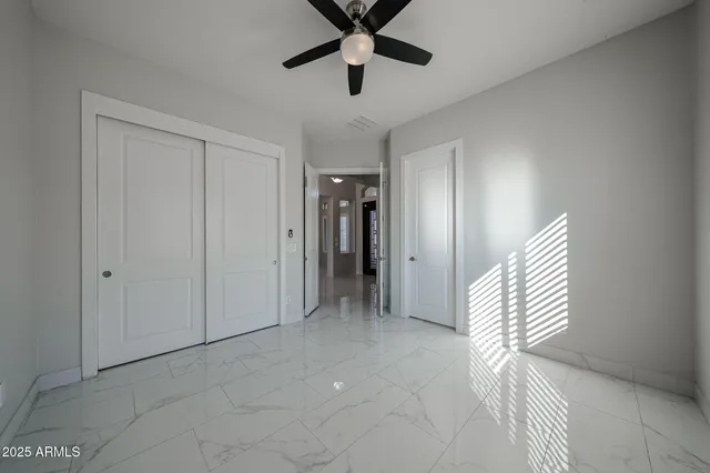 a view of an empty room with window and a chandelier fan