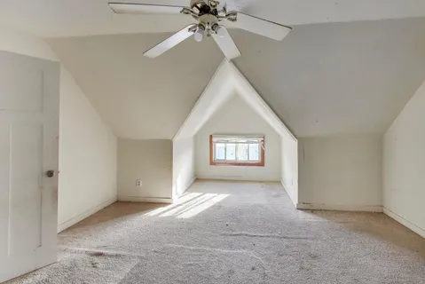 an empty room with a ceiling fan and window
