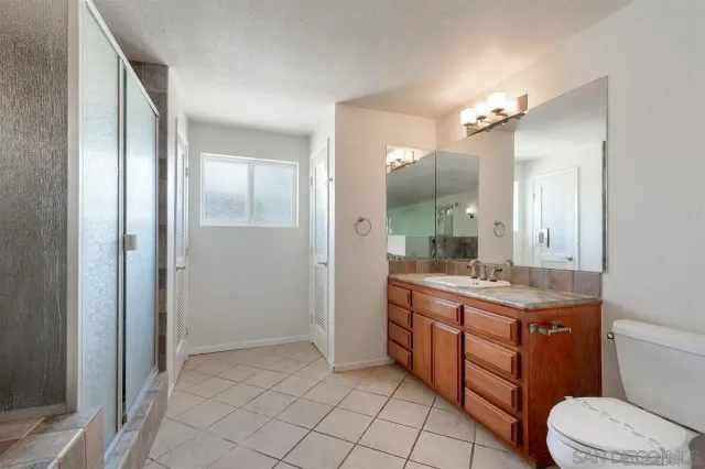 a bathroom with a granite countertop toilet sink and mirror