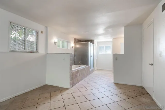 a view of a refrigerator in kitchen and an empty room