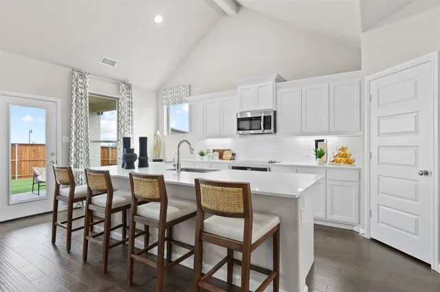 a kitchen with white cabinets and chairs