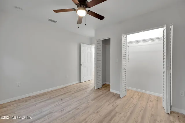 an empty room with wooden floor closet and ceiling fan