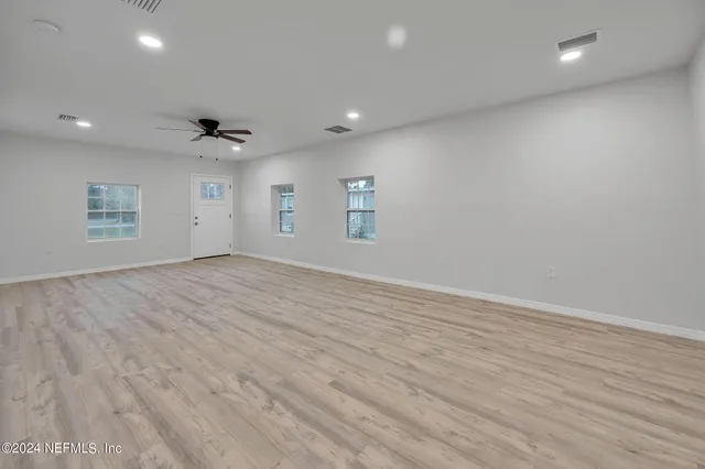 an empty room with wooden floor and windows