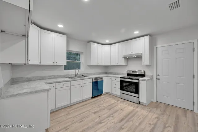 a kitchen with stainless steel appliances granite countertop a stove and white cabinets