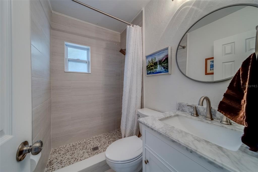 11424 79th Avenue Seminole, FL 33772 - Photo 33 of 62 a bathroom with a granite countertop sink a mirror a toilet and a shower