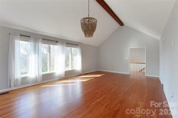 a view of an empty room with window and wooden floor