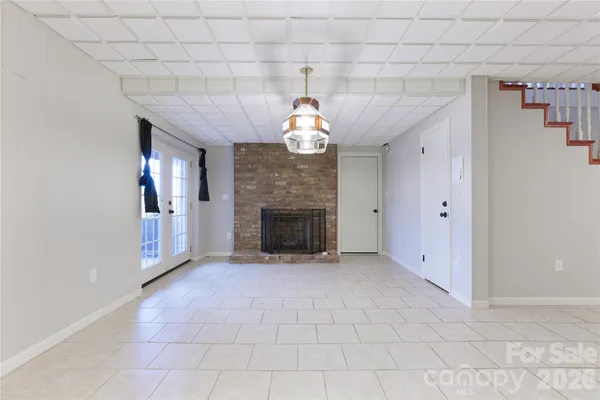 a view of an empty room with a fireplace and a chandelier